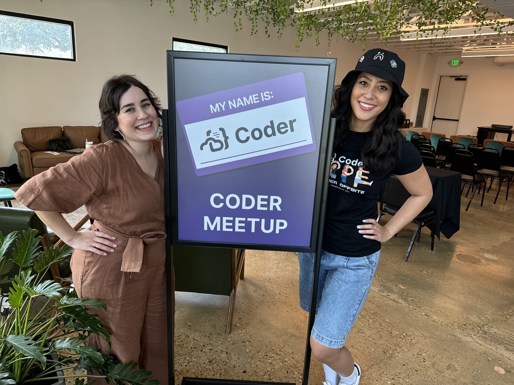 2 people posing next to a sign labeled 'CODER MEETUP', with an image of a nametag saying 'MY NAME IS: Coder'