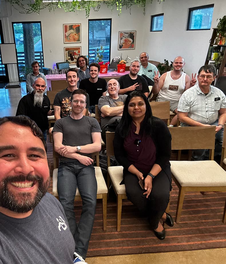 Selfie taken by a Coder employee at an in-person meetup, in front of a smiling seated audience of 12.
