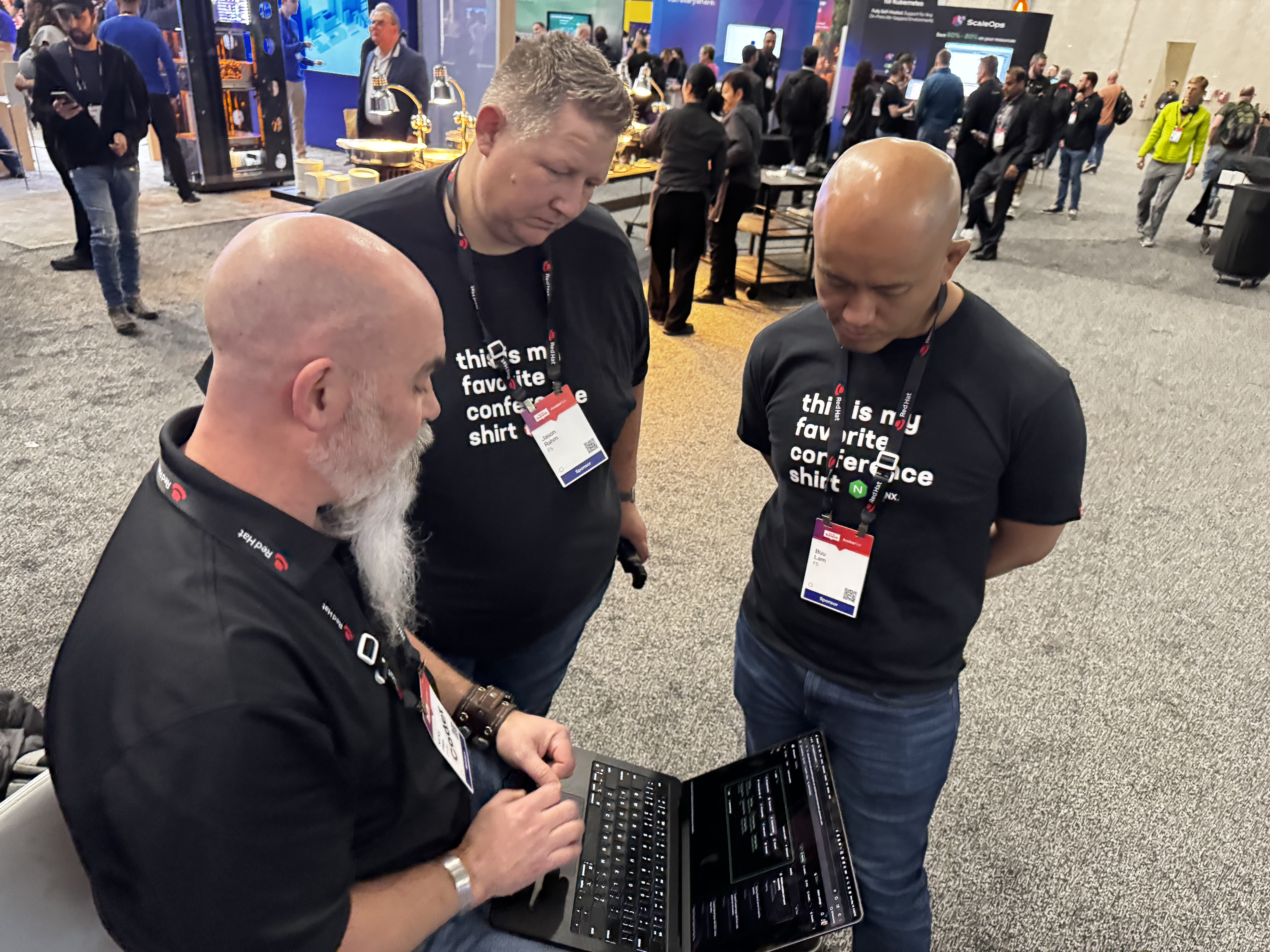 3 people in a conference hall wearing lanyards, huddled around a laptop showing a Coder workspace