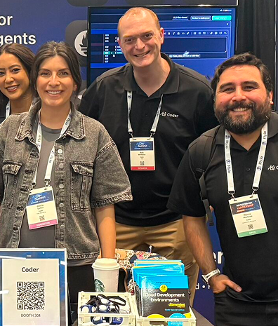 4 people in lanyards smiling at a conference table