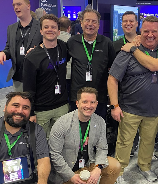 several people posing together dressed in Coder shirts and conference lanyards